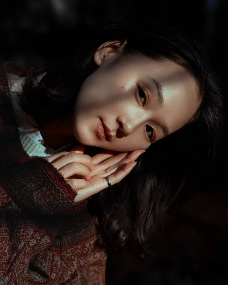 Licht und Schatten Portrait einer asiaten Frau die Ihren Kopf auf die Hände legt